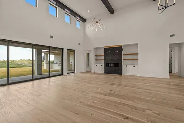 a view of an empty room with a window and a kitchen