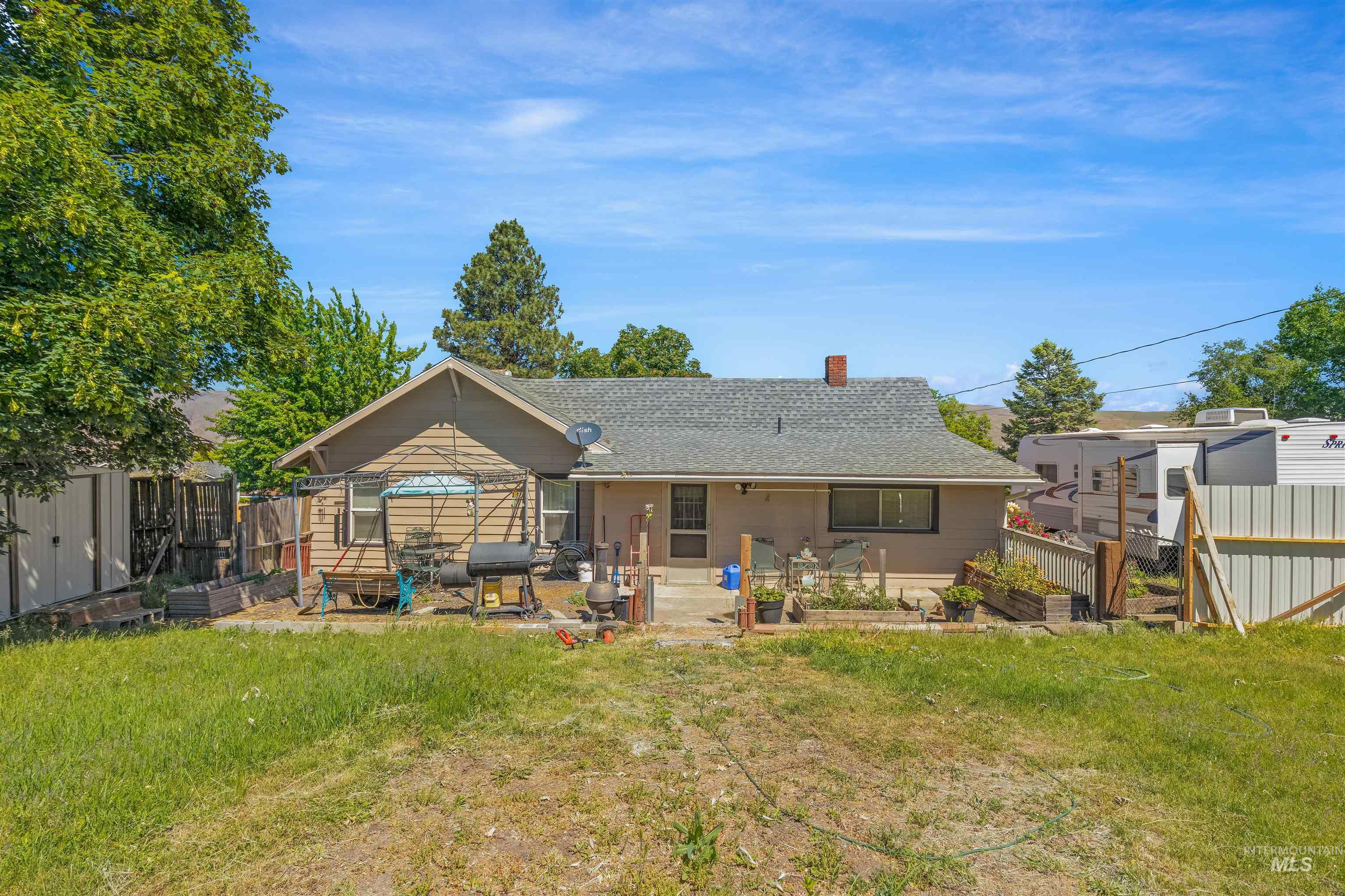 238 Hillcrest Road Lewiston, ID 83501 - Photo 3 of 27 Rear exterior featuring a patio area with raised garden beds and a detached storage shed