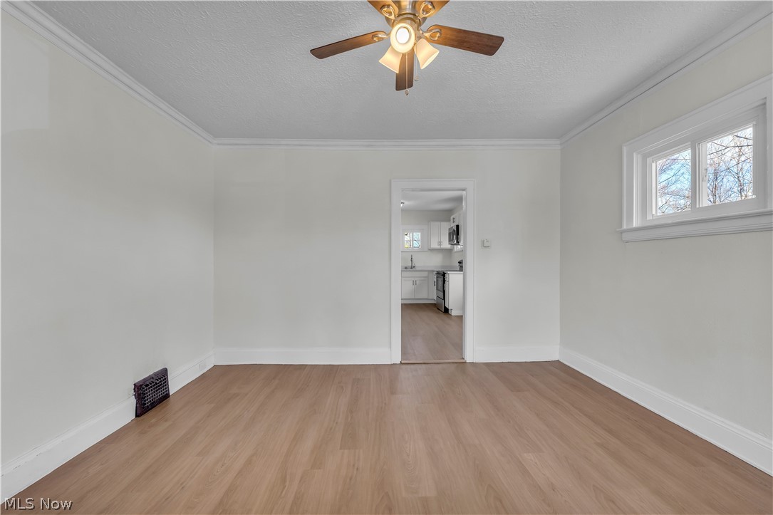 12905 Watterson Avenue Cleveland, OH 44105 - Photo 13 of 30 Spare room featuring a textured ceiling, light wood-style floors, ceiling fan, and crown molding
