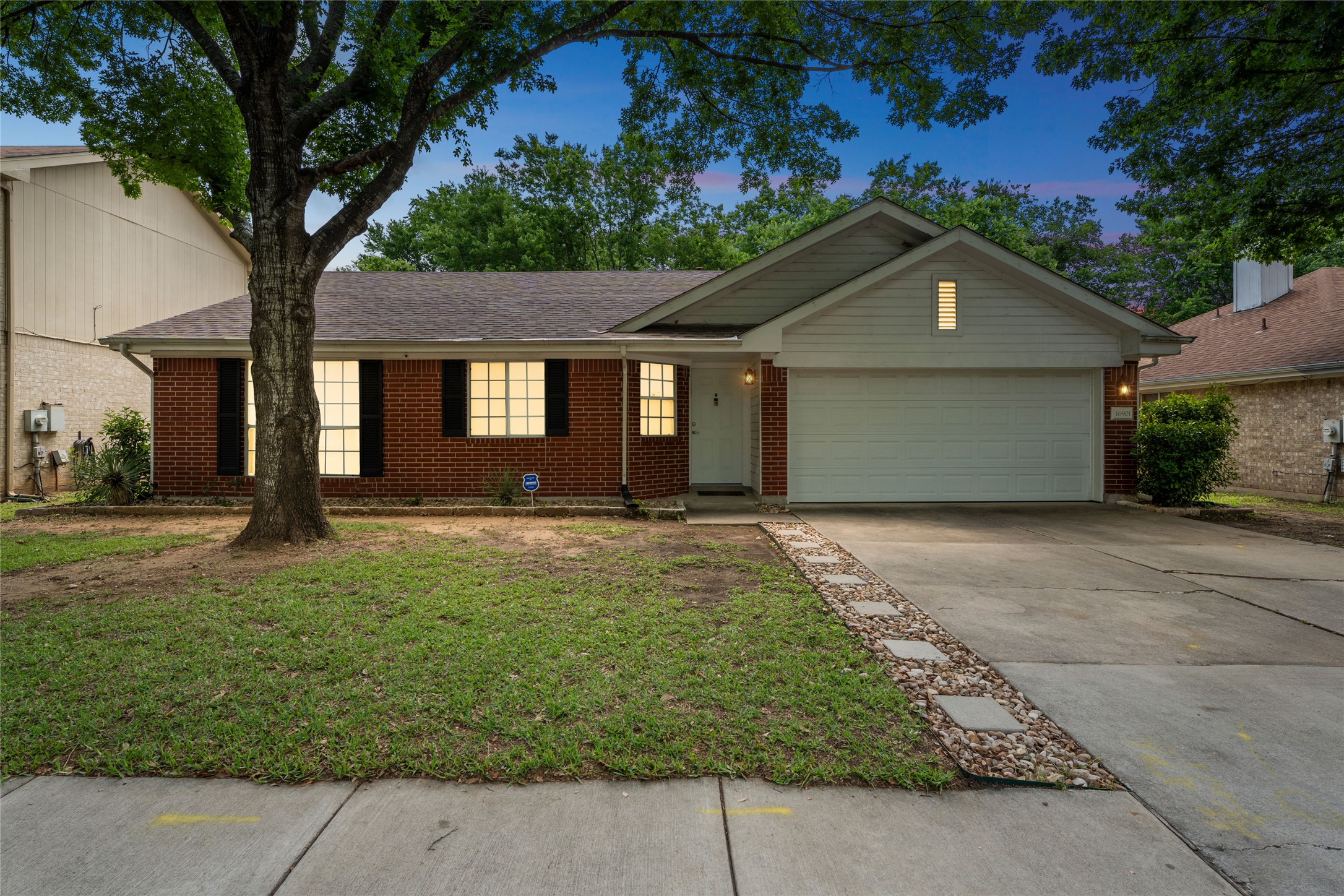 16901 Gower Street Pflugerville, TX 78660 - Photo 1 of 1 This ranch-style home features a driveway, shingled roof, lush lawn, brick siding, and a two-car garage.