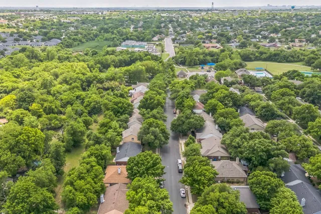 an aerial view of residential houses with outdoor space and trees
