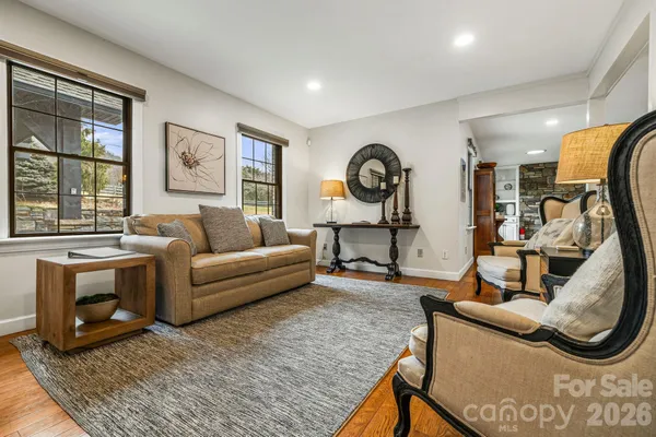 a living room with furniture a clock on wall and a window