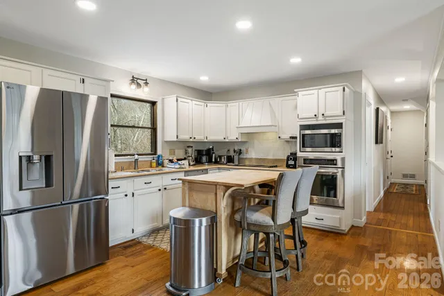 a kitchen with stainless steel appliances a refrigerator a stove a sink and white cabinets