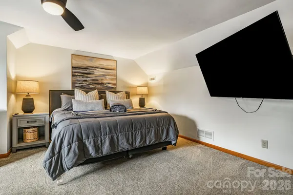 a bedroom with a bed and flat tv screen on dresser