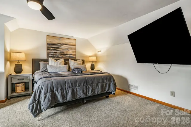 a bedroom with a bed and flat tv screen on dresser