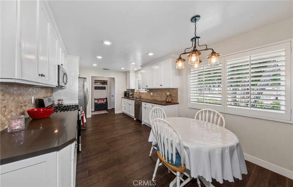 13689 Bryant Street Yucaipa, CA 92399 - Photo 7 of 30 a kitchen with stainless steel appliances kitchen island granite countertop a stove a sink a refrigerator and white cabinets with wooden floor