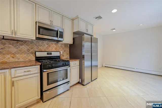 a kitchen with stainless steel appliances granite countertop a stove a refrigerator and a microwave