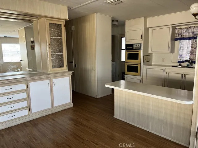 a large kitchen with stainless steel appliances a large counter top and a wooden floors