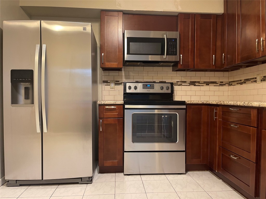 9217 Carousel Lane Houston, TX 77080 - Photo 37 of 38 a kitchen with granite countertop wooden cabinets and stainless steel appliances
