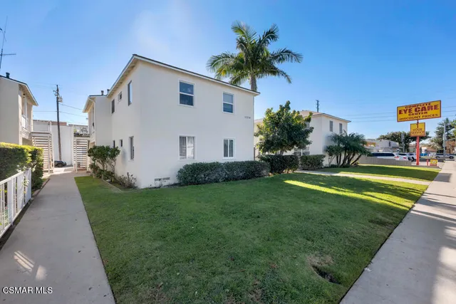 a front view of a house with a yard and palm trees