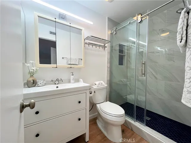a bathroom with a toilet a sink a mirror a shower and vanity