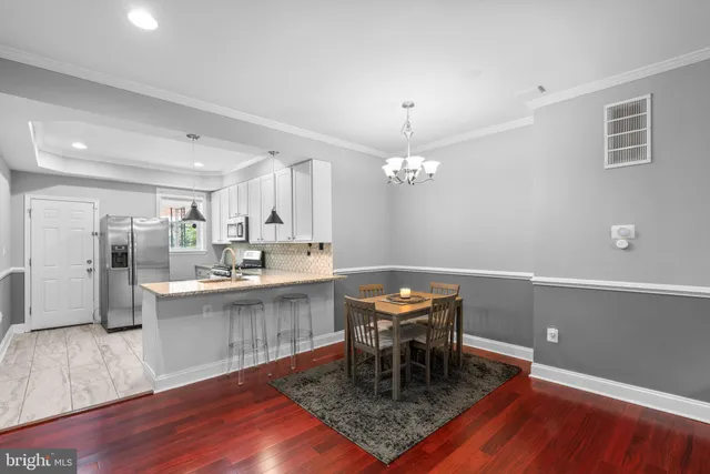 a dining room with chandelier and wooden floor