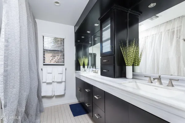 a bathroom with a double vanity sink mirror and bathtub
