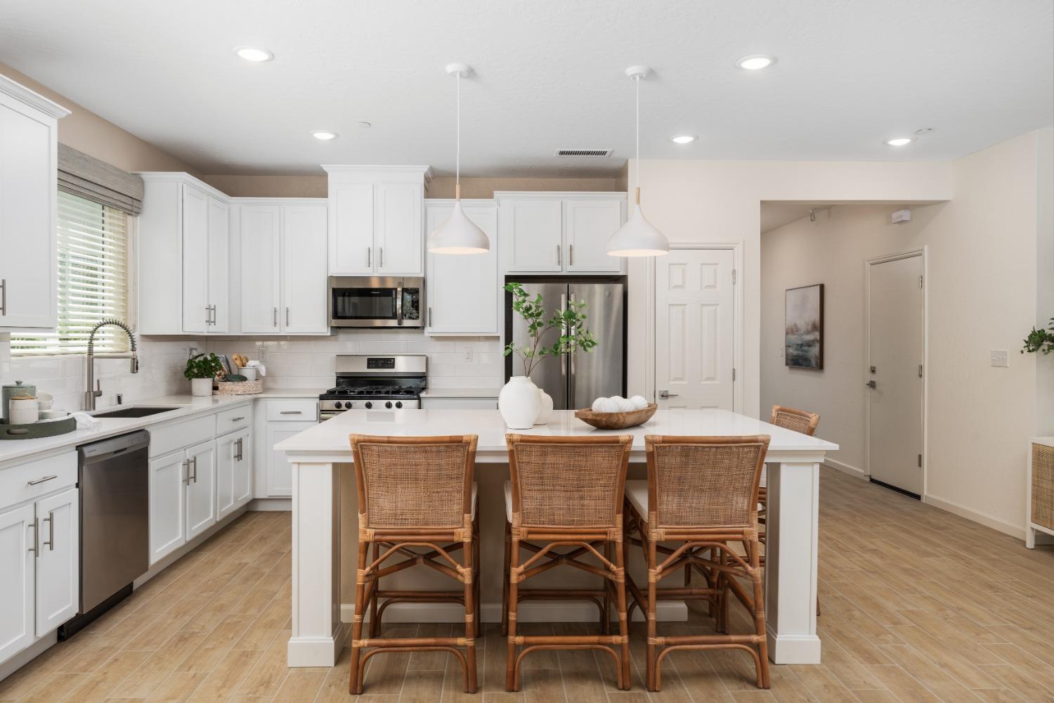 a kitchen with stainless steel appliances kitchen island granite countertop a dining table chairs refrigerator and sink
