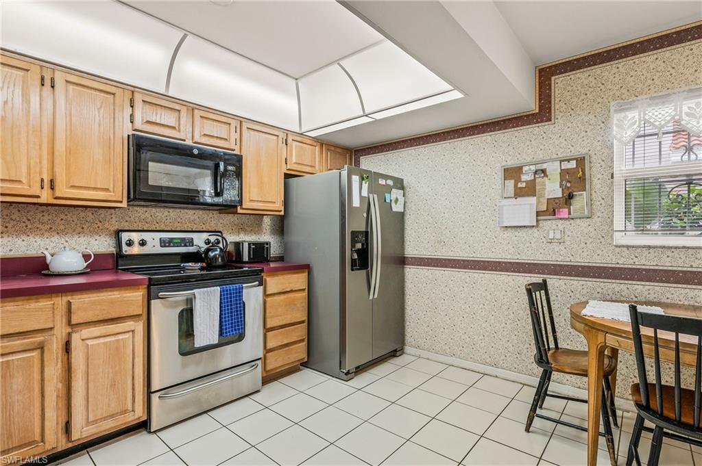156 Sabal Lake Drive Naples, FL 34104 - Photo 13 of 40 a kitchen with stainless steel appliances granite countertop a stove a sink dishwasher a refrigerator and a microwave