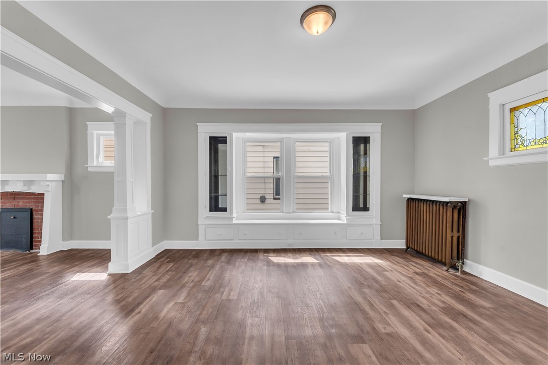 3506 Riverside Avenue Cleveland, OH 44109 - Photo 8 of 31 Spacious room featuring wood-finish flooring, a built-in window seat with storage, white trim, and a stained glass window