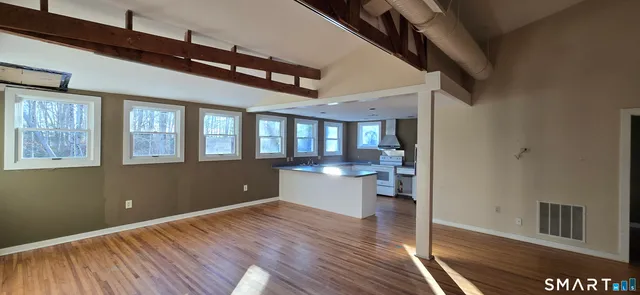 a view of an empty room with a window and wooden floor