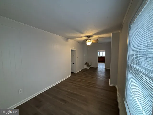 a view of a livingroom with wooden floor a ceiling fan and staircase