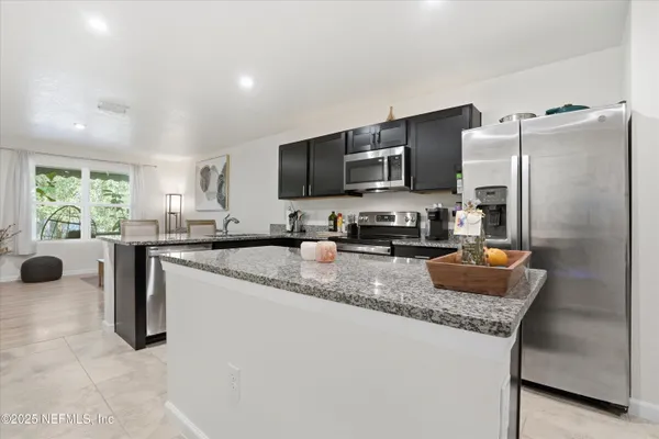 a kitchen with stainless steel appliances granite countertop a sink refrigerator and microwave