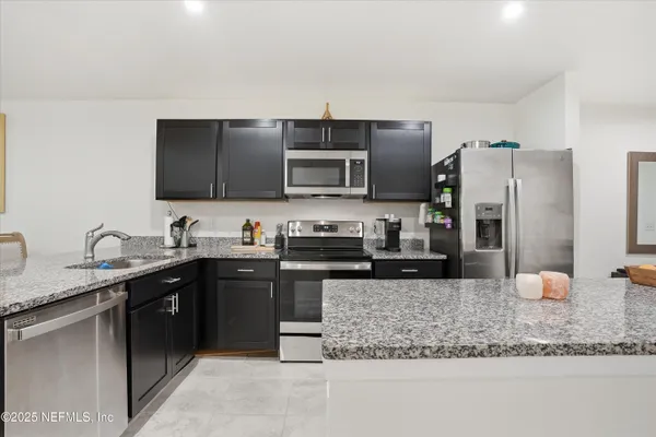 a kitchen with stainless steel appliances granite countertop a sink stove and refrigerator