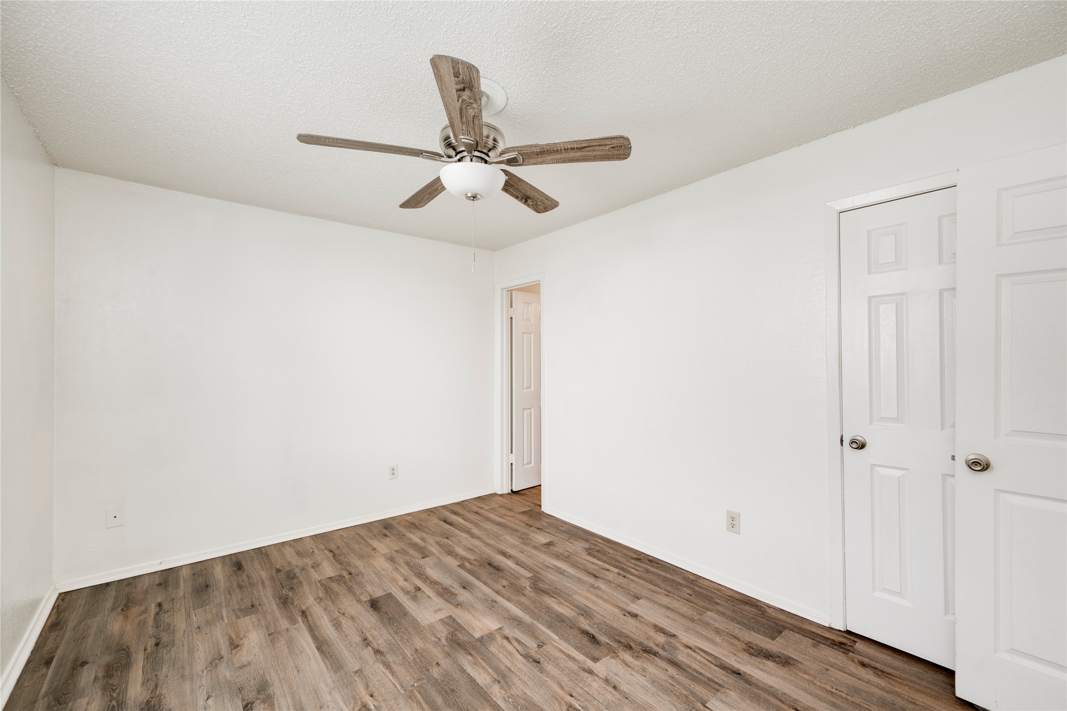 7918 West Gate Boulevard Austin, TX 78745 - Photo 12 of 31 A quiet bedroom featuring elegant wood-look flooring and a functional ceiling fan with lighting.