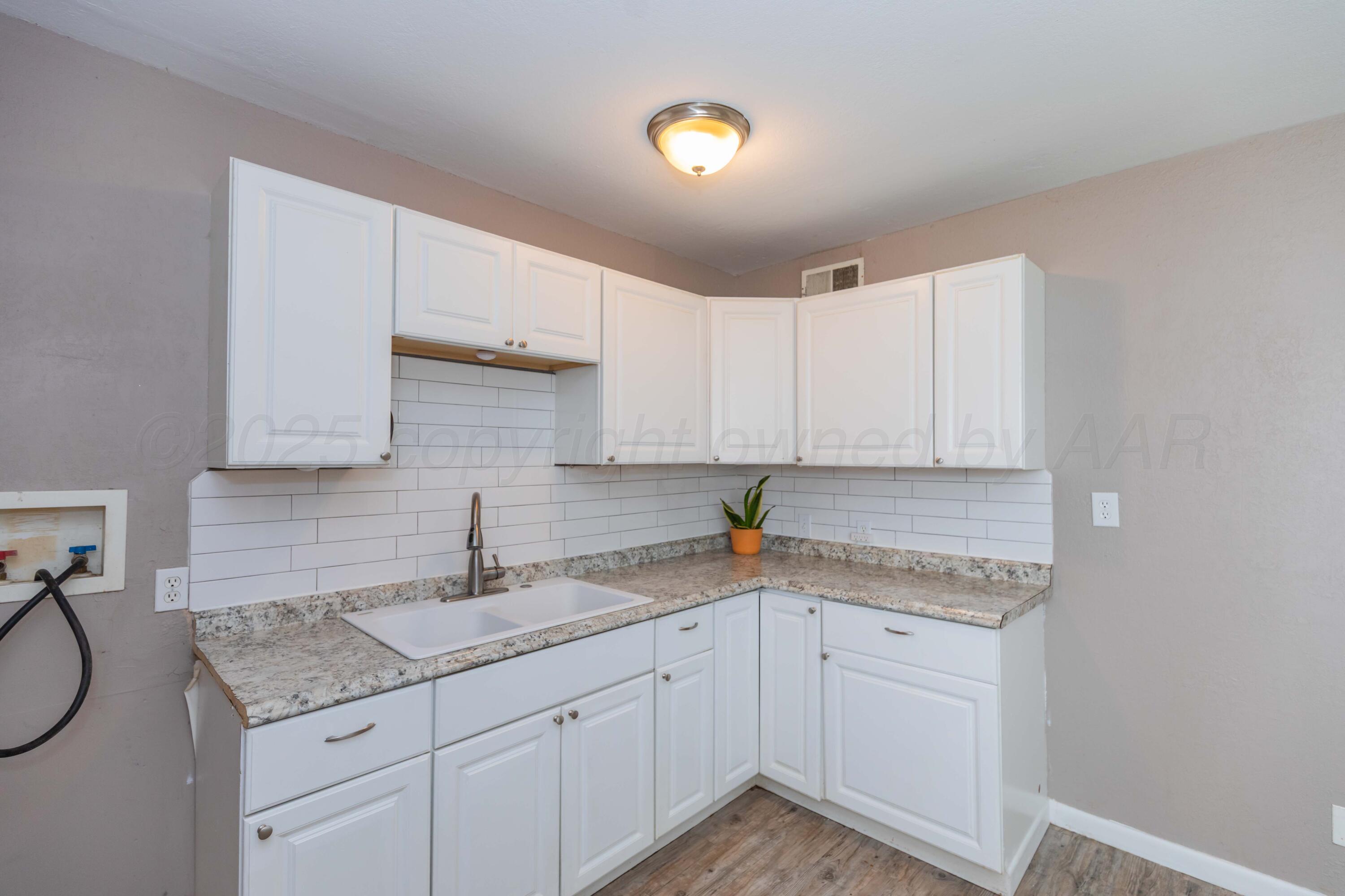2138 North Sumner Street Pampa, TX 79065 - Photo 11 of 30 a kitchen with granite countertop white cabinets and white appliances