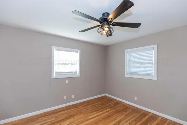 a view of a big room with wooden floor and windows