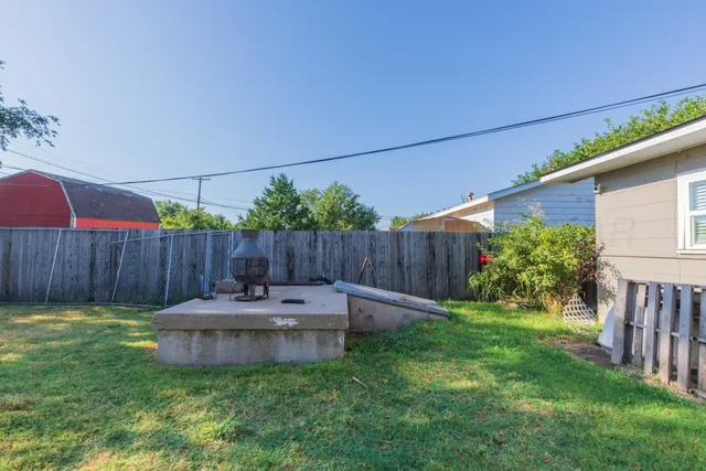 a view of a backyard with plants and wooden fence