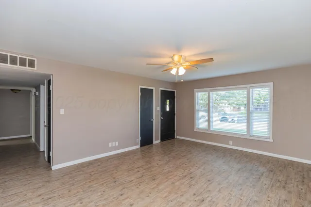 a view of an empty room with chandelier fan and fire place