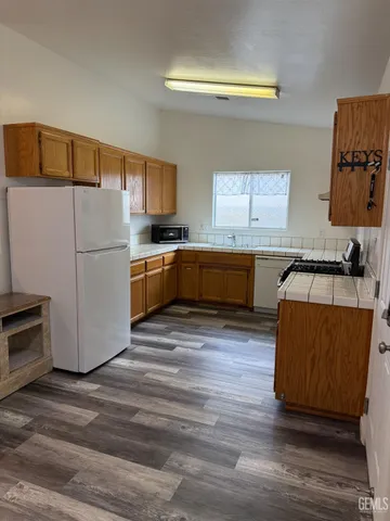 a kitchen with granite countertop a refrigerator stove top oven and sink
