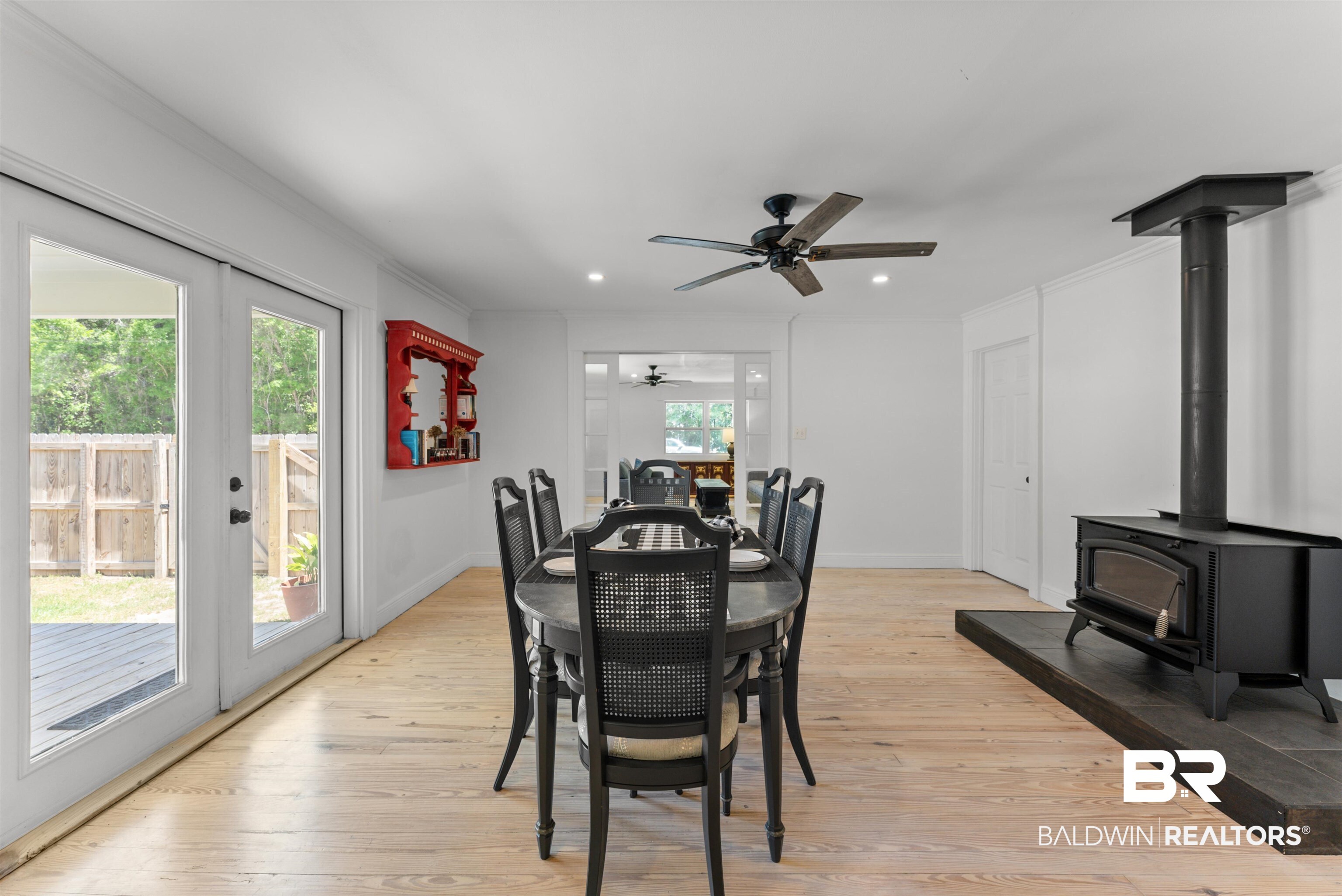 6447 Bemis Lane Bon Secour, AL 36511 - Photo 23 of 62 Dining area featuring light wood-finish flooring, a black wood-burning stove on a dark hearth, and a ceiling fan