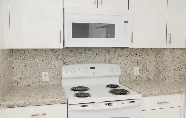 a kitchen with granite countertop cabinets and white appliances