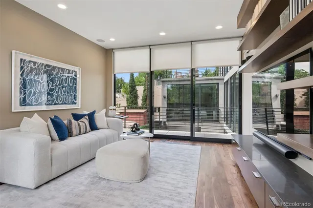 a living room with furniture a large window and wooden floor