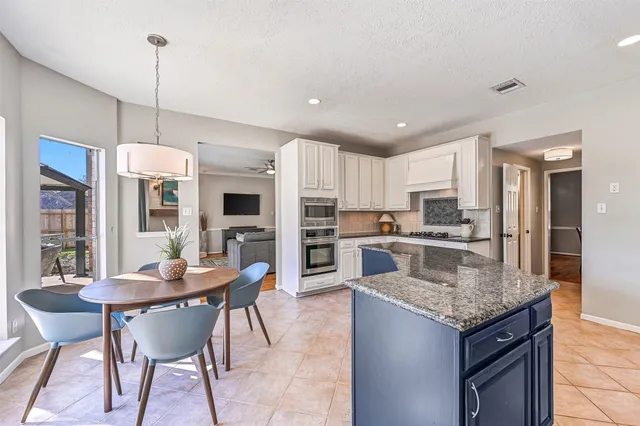a kitchen with granite countertop kitchen island dining table and stainless steel appliances