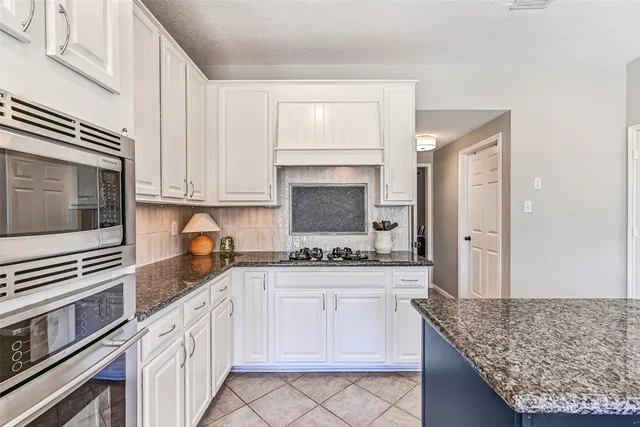 a kitchen with granite countertop a sink stove and cabinets