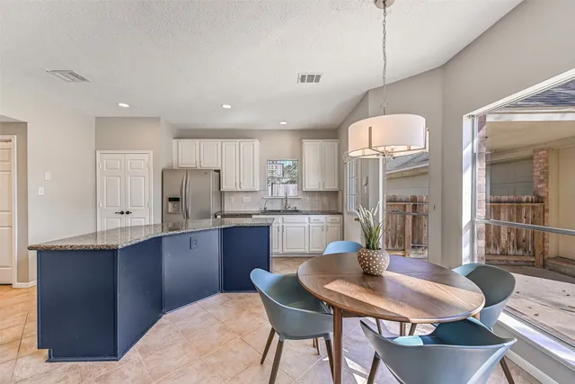 a kitchen with stainless steel appliances granite countertop a sink a stove a refrigerator with a dining table and chairs