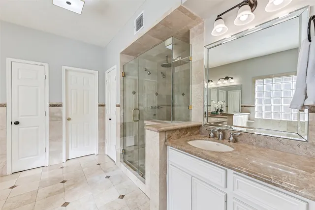 a bathroom with a sink vanity granite tub shower and a mirror