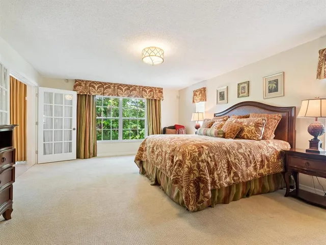 a bed sitting in a spacious bedroom next to a window