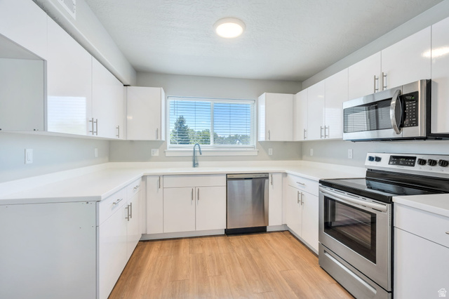 572 South 100 West, Unit E210 Springville, UT 84663 - Photo 14 of 35 Contemporary kitchen featuring white cabinetry, light countertops, wood-finish flooring, a stainless steel electric range, and a built-in microwave