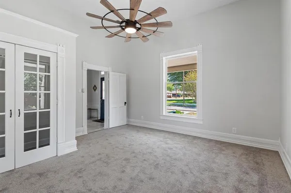 an empty room with chandelier fan and windows