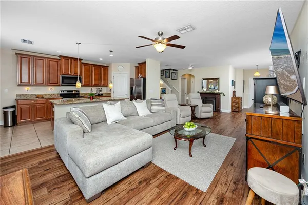 a living room with furniture kitchen view and a wooden floor