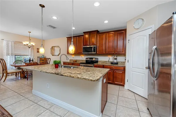 a kitchen with stainless steel appliances granite countertop a refrigerator a stove a sink a dining table and chairs