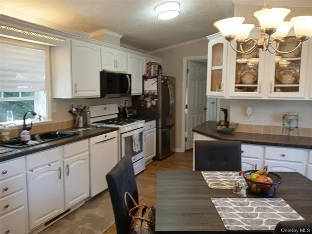 a kitchen with stainless steel appliances granite countertop a sink dishwasher a microwave oven and a dining table with wooden floor