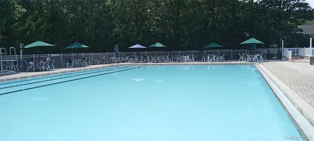 a view of swimming pool with table and chairs under an umbrella