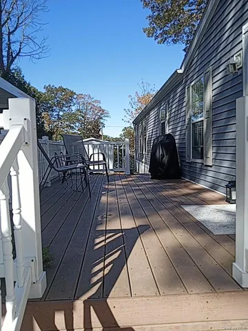 a view of a roof deck with table and chairs a barbeque with wooden floor and fence
