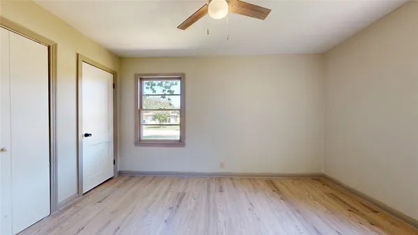 an empty room with a hardwood and ceiling fan
