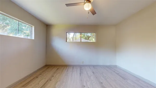 an empty room with wooden floor and windows