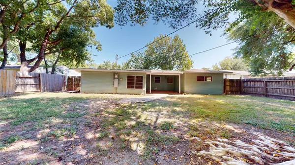 a view of a house with a yard and a large tree
