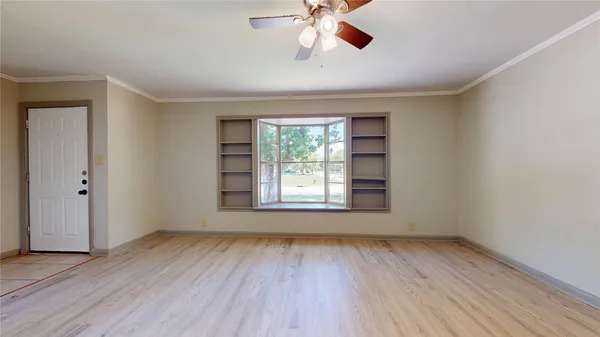 a view of an empty room with wooden floor and a window