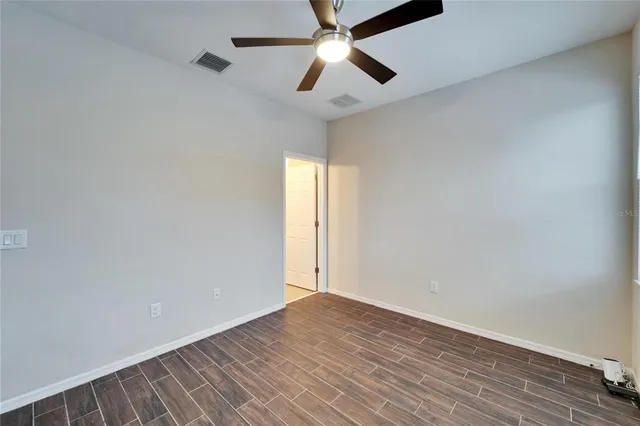 a view of empty room with wooden floor and fan